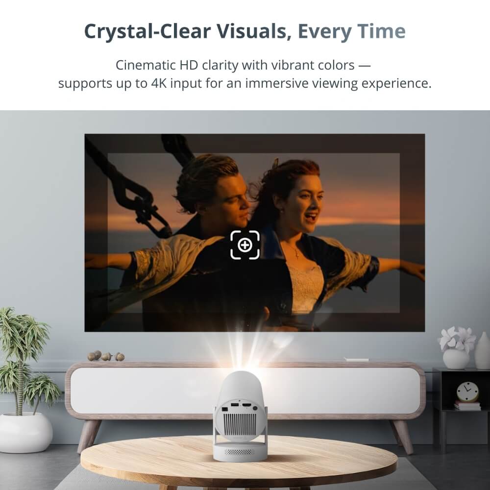Photograph of a sleek white projector on a wooden coffee table emitting a bright light beam onto a wall in a minimalist living room, displaying the iconic James Cameron's Titanic scene of Jack and Rose on the ship's bow with vibrant orange and blue sunset hues