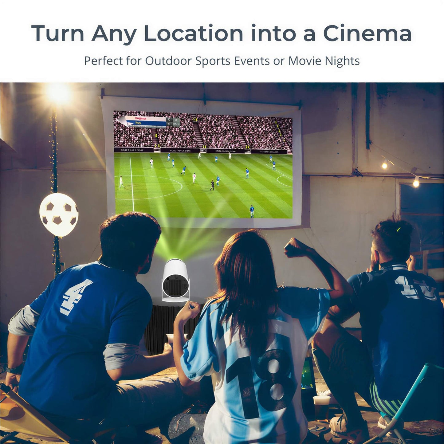 A portable projector displays a soccer game on a white sheet for three friends watching on an outdoor patio, surrounded by string lights and a soccer ball-shaped lamp, wearing blue sports jerseys with numbers 4, 18, and 13