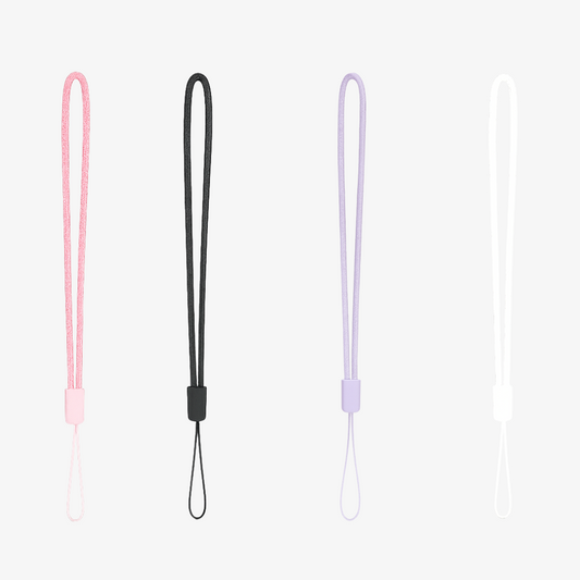 Studio product shot of four braided wrist straps in pastel pink, black, lavender, and white, each with a small plastic adjuster on a light gray background