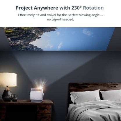 A white portable projector beams a rocky mountain and blue sky scene onto a dark bedroom ceiling beside a wooden nightstand with a lamp and a bed with white pillows