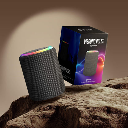 Product photograph of a grey mesh VISOUND PULSE by VionB Portable Bluetooth Speaker with a rainbow LED light ring and its black box featuring a vibrant blue-purple-orange gradient design, both displayed on a textured rocky brown surface