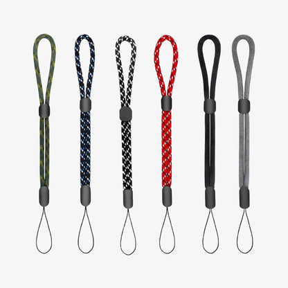 Photography of six braided wrist straps featuring adjustable black sliders and diverse patterns including green camouflage, blue geometric, red geometric, solid black, and solid grey