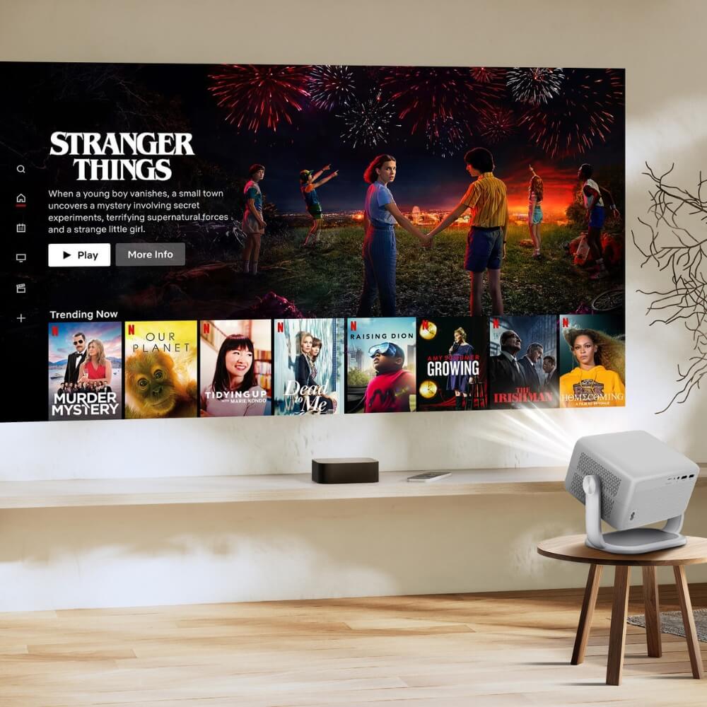Digital projection of the Netflix interface displaying Stranger Things with its iconic kids and fireworks scene, alongside trending shows like Our Planet and Tidying Up, all cast onto a minimalist wall by a white portable projector in a modern living space