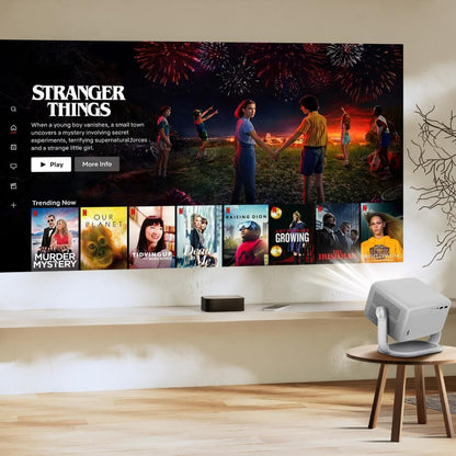 Digital projection of the Netflix interface displaying Stranger Things with its iconic kids and fireworks scene, alongside trending shows like Our Planet and Tidying Up, all cast onto a minimalist wall by a white portable projector in a modern living space