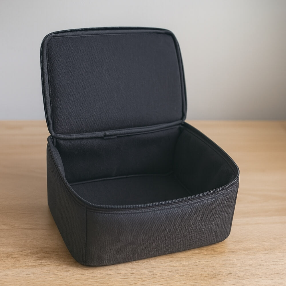 Photograph of an open empty black textile zippered case with a padded interior sitting on a light wooden desk against a soft gray wall