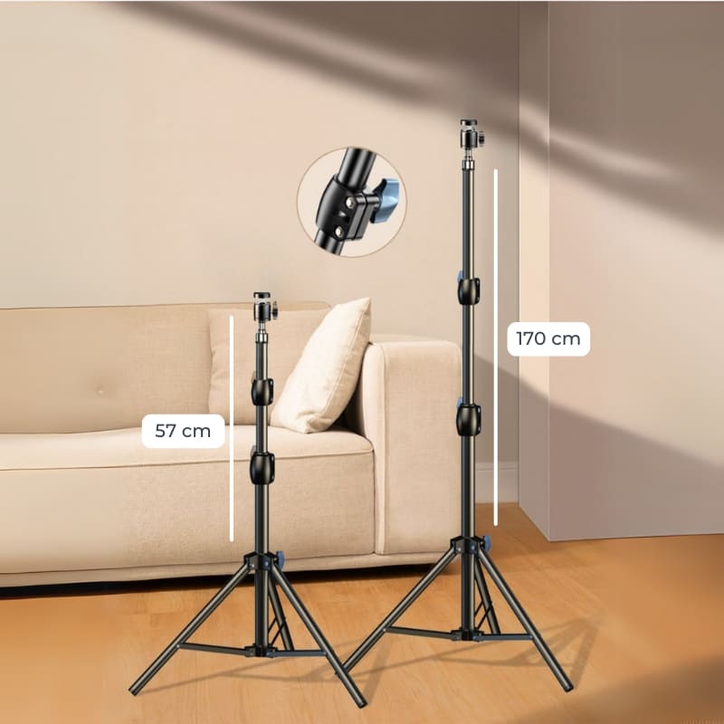 Two black adjustable tripods displayed indoors showing a collapsed 57 cm height and an extended 170 cm height, with a circular inset highlighting a blue locking mechanism and a beige sofa in the background