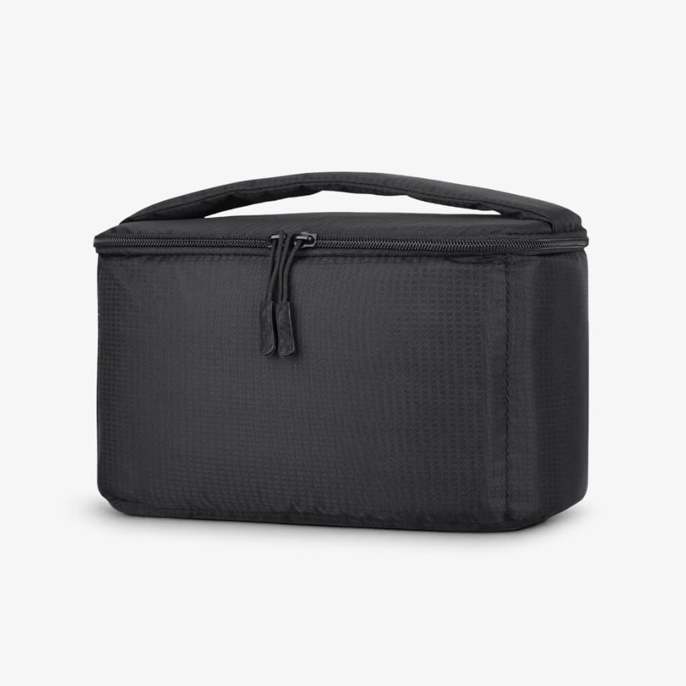 A black rectangular soft-sided bag featuring a textured ripstop fabric, a top zipper with two black pull tabs, and a padded carry handle against a white studio background