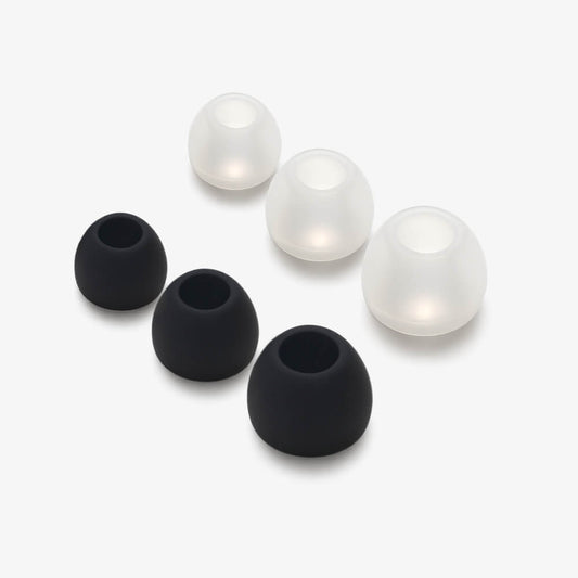 Six dome-shaped earbud tips, three matte black and three glowing translucent white, arranged on a clean white surface