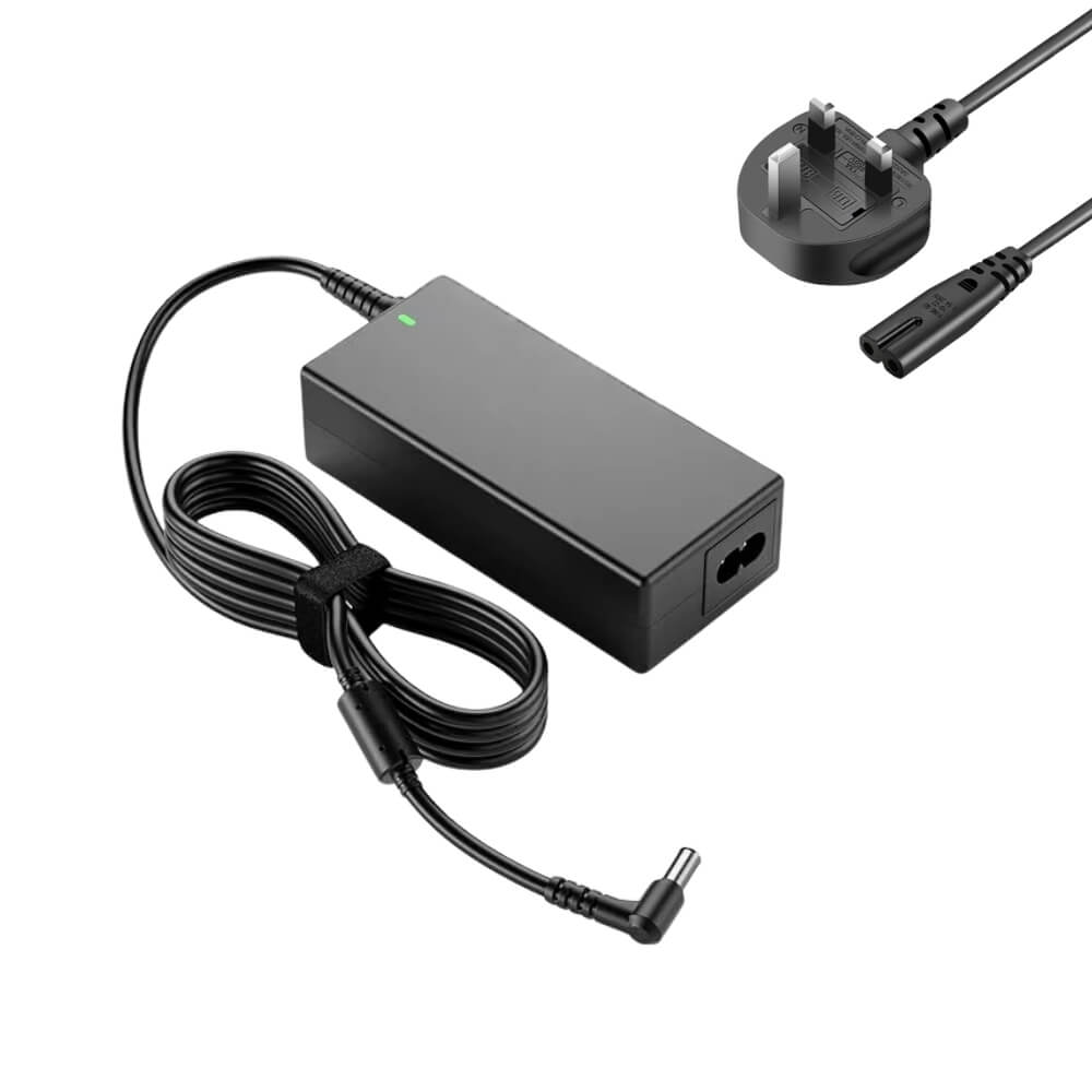 Digital photograph of a black laptop power adapter featuring a green LED light, a coiled cable secured with a Velcro strap leading to a 90-degree DC barrel plug, and a detachable UK Type G three-pin power cord with a C8 connector