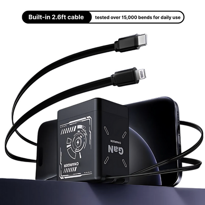 Black GaN charger with white circuit graphics and "GaN CHARGER" text, featuring integrated 2.6ft USB-C and Lightning cables, positioned on a dark blue surface next to a black smartphone