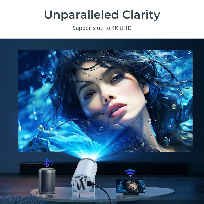 Digital product advertisement showing a white home projector on a table with a bright blue light beam projecting a vivid image of a woman's face with flowing dark hair immersed in sparkling blue water and bubbles onto a wall, flanked by a wireless gray speaker and a smartphone mirroring the display